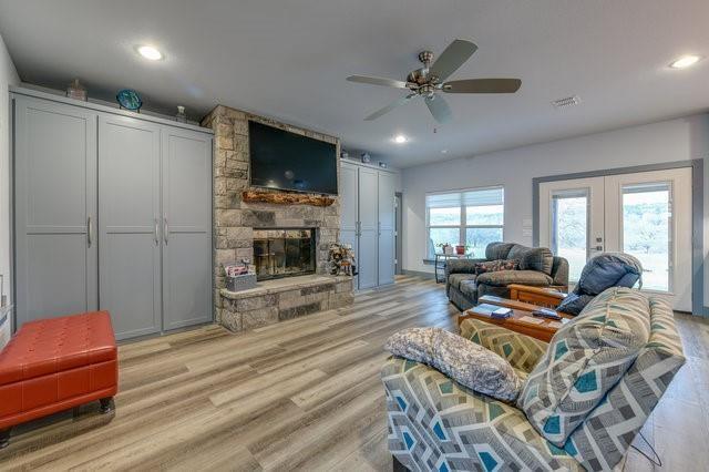 living area featuring light wood finished floors, visible vents, french doors, a fireplace, and recessed lighting