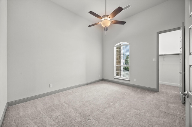 carpeted empty room with high vaulted ceiling and ceiling fan