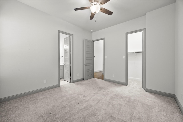 unfurnished bedroom featuring ensuite bath, ceiling fan, light carpet, a walk in closet, and a closet