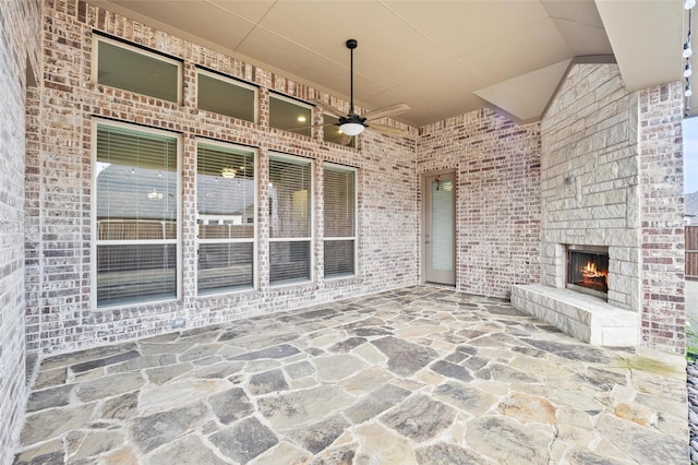 view of patio / terrace featuring ceiling fan and a large fireplace