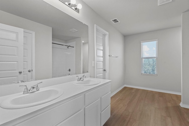 bathroom with vanity, wood-type flooring, and tiled shower