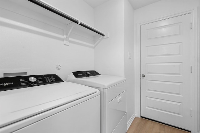 laundry area with washer and dryer and light wood-type flooring