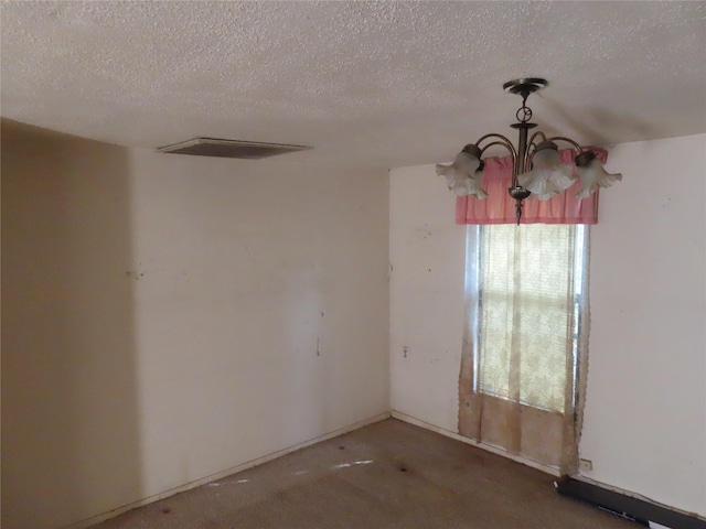 carpeted spare room featuring a textured ceiling and a chandelier