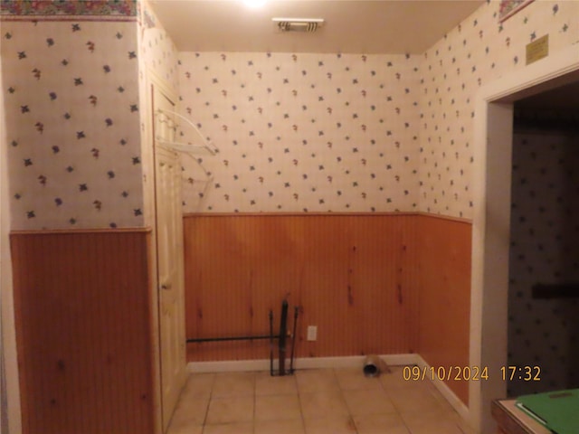 bonus room with light tile patterned flooring and wood walls