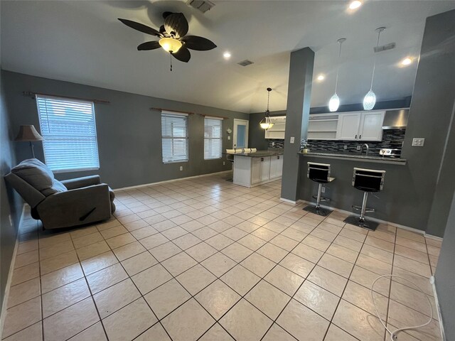 living room featuring lofted ceiling, ceiling fan, light tile patterned floors, and sink