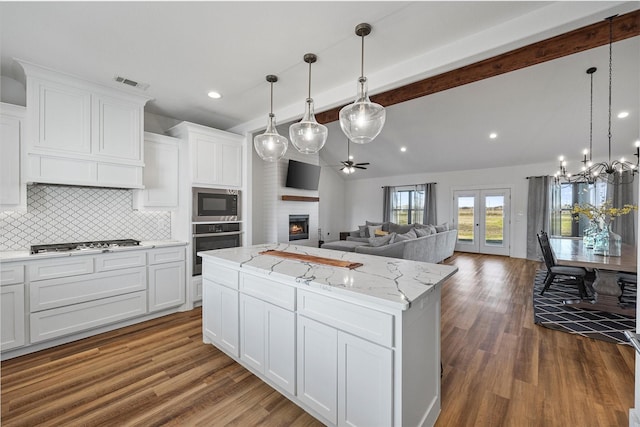 kitchen with stainless steel appliances, a kitchen island, and white cabinetry