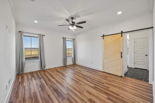 unfurnished room featuring ceiling fan, ornamental molding, a wealth of natural light, and a barn door