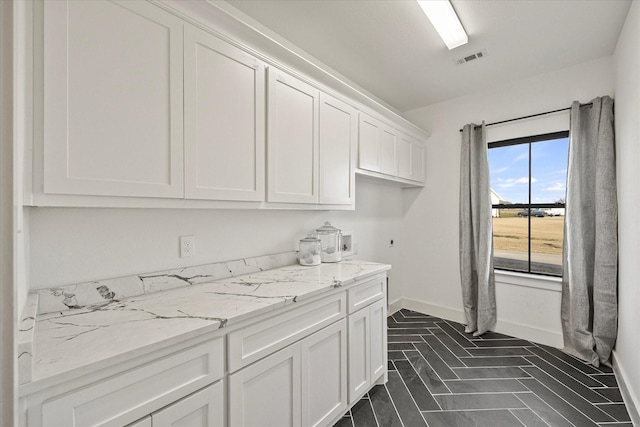 laundry room with electric dryer hookup and cabinets