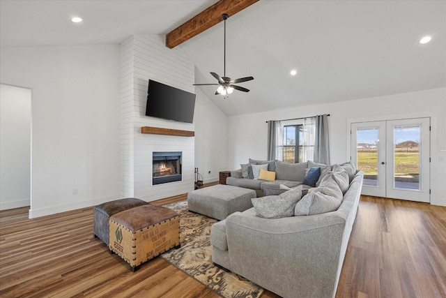 living room featuring lofted ceiling with beams, ceiling fan, french doors, a fireplace, and hardwood / wood-style flooring