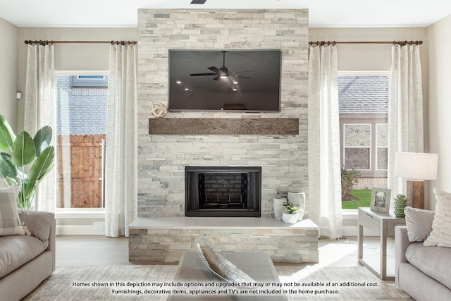 living room with a healthy amount of sunlight, a stone fireplace, and wood-type flooring