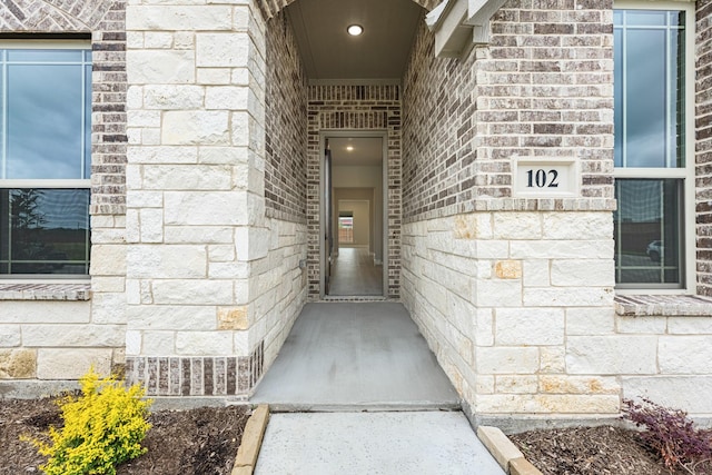 view of exterior entry featuring stone siding and brick siding