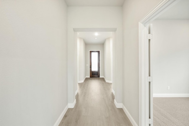 hallway with baseboards and light wood-style floors