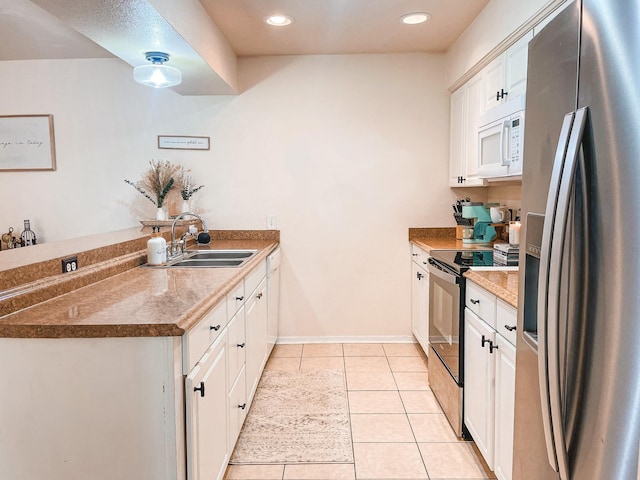 kitchen featuring electric range oven, stainless steel refrigerator with ice dispenser, white cabinetry, light tile patterned flooring, and sink