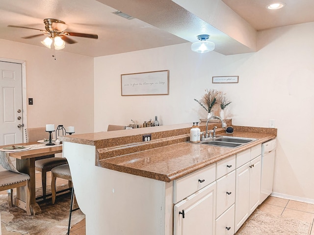 kitchen featuring sink, white cabinetry, dishwasher, a kitchen bar, and kitchen peninsula