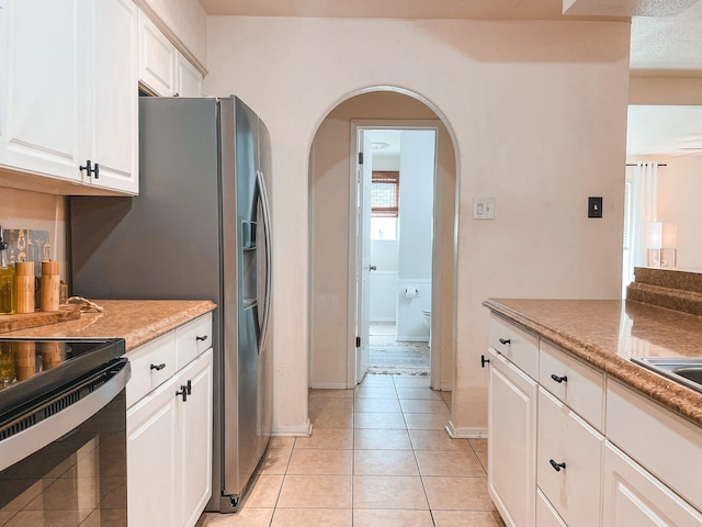 kitchen featuring light tile patterned floors, black range with electric cooktop, and white cabinetry