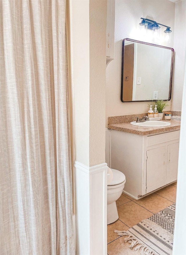 bathroom featuring curtained shower, tile patterned flooring, vanity, and toilet