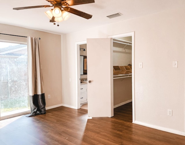 unfurnished bedroom featuring ceiling fan, dark hardwood / wood-style flooring, a spacious closet, and a closet