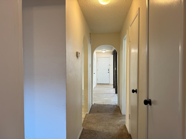 hall featuring a textured ceiling and carpet floors