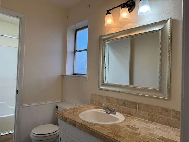 bathroom with a bathtub, vanity, and toilet