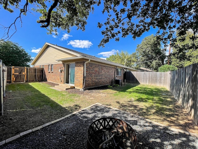 back of property featuring an outdoor fire pit and a lawn