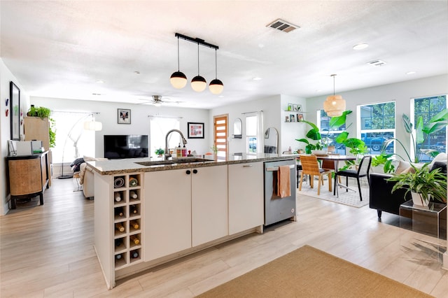 kitchen featuring sink, an island with sink, decorative light fixtures, and white cabinetry