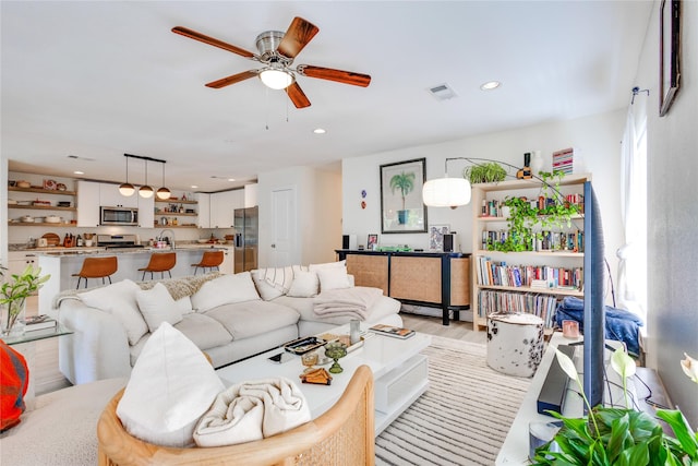 living room with sink, ceiling fan, and light hardwood / wood-style flooring