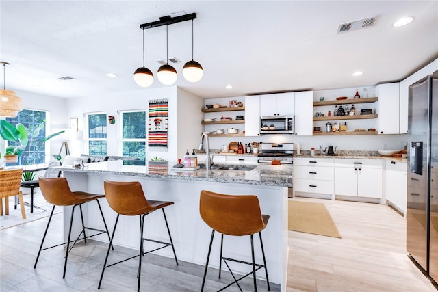 kitchen featuring white cabinets, pendant lighting, light wood-type flooring, and appliances with stainless steel finishes