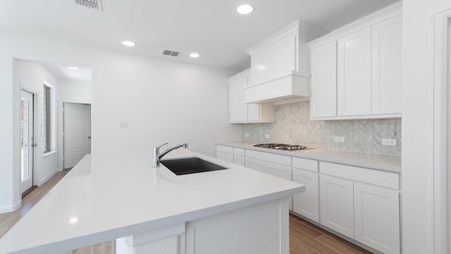 9328 Paintbrush Dr, Oak Point, TX 75068 - kitchen featuring a sink, stainless steel gas cooktop, decorative backsplash, wood finished floors, and white cabinetry