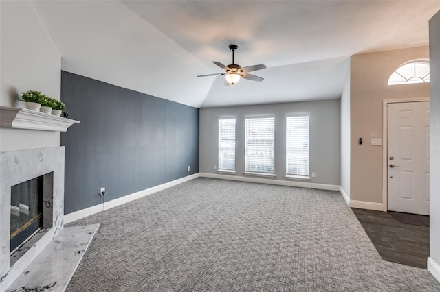 unfurnished living room featuring lofted ceiling, a fireplace, ceiling fan, and dark colored carpet