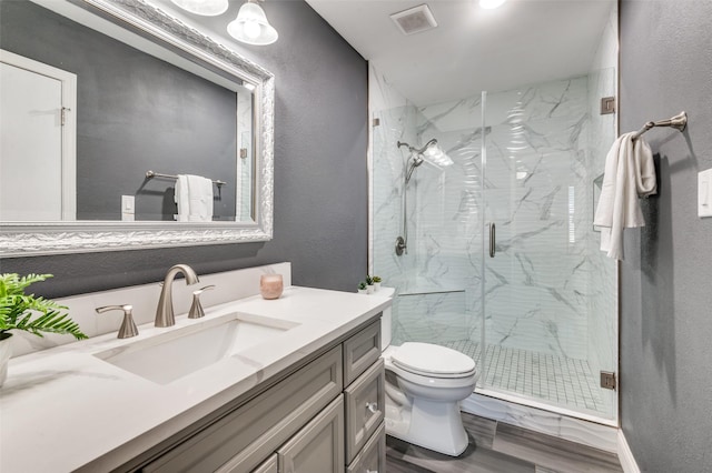 bathroom featuring vanity, hardwood / wood-style flooring, a shower with shower door, and toilet