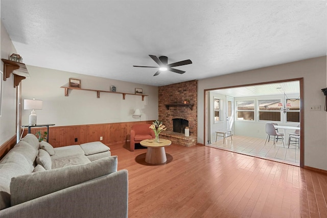 living room featuring hardwood / wood-style floors, a fireplace, a textured ceiling, and ceiling fan