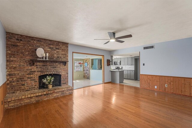 living room featuring ceiling fan, hardwood / wood-style floors, and a brick fireplace