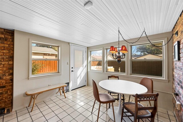 dining room with light tile patterned floors, brick wall, and a wealth of natural light