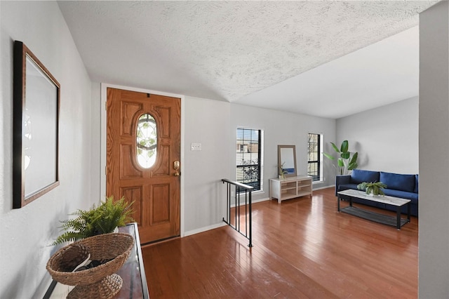 entrance foyer with a textured ceiling, baseboards, and wood finished floors