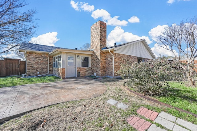 back of house featuring a patio area, a chimney, fence, and brick siding