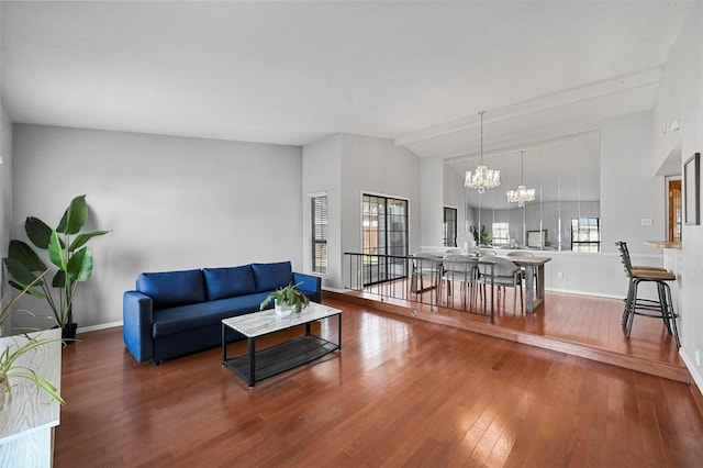 living room featuring wood-type flooring, vaulted ceiling, baseboards, and an inviting chandelier