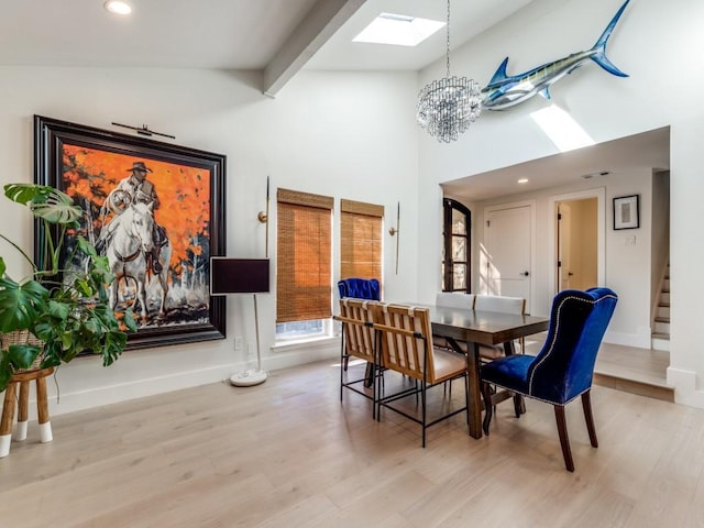 dining room featuring a chandelier, light hardwood / wood-style floors, high vaulted ceiling, a skylight, and beamed ceiling