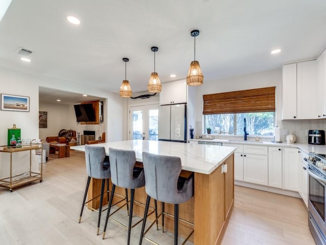 kitchen featuring sink, a center island, white fridge, and white cabinetry