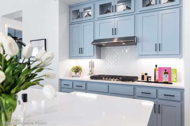 kitchen featuring blue cabinets, stainless steel gas cooktop, and backsplash