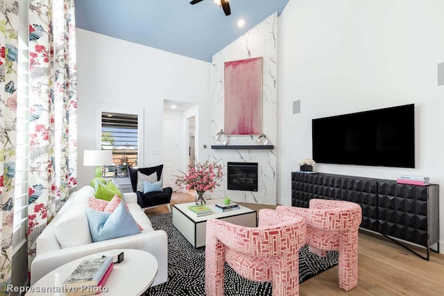 living room featuring a fireplace, high vaulted ceiling, ceiling fan, and light hardwood / wood-style floors