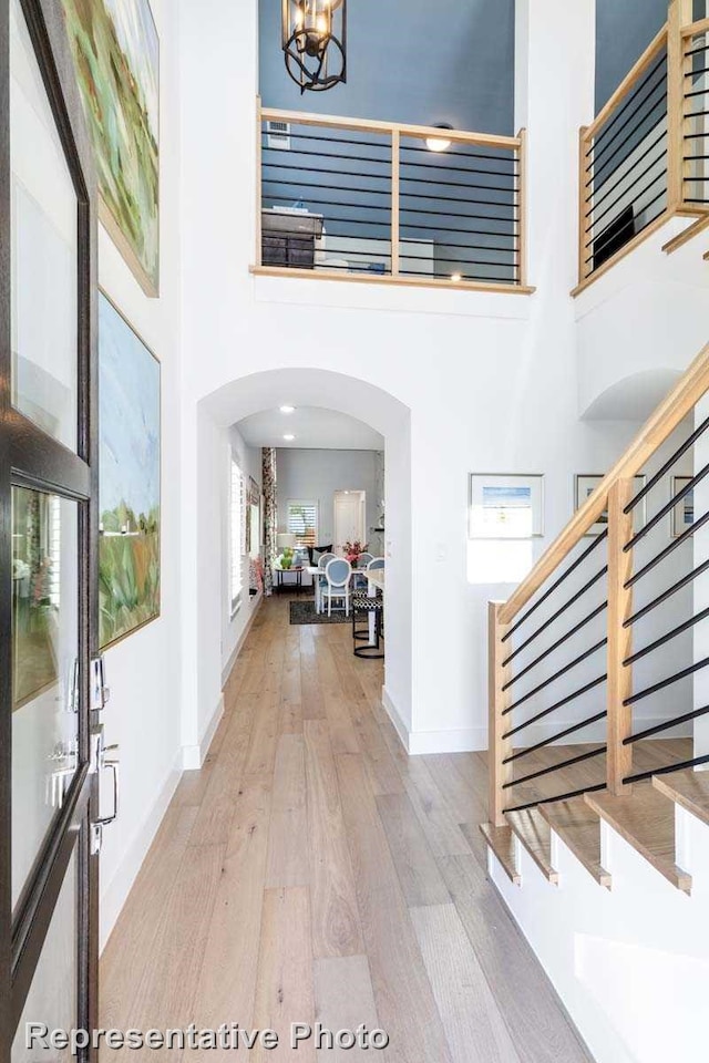 foyer with a notable chandelier, light wood-type flooring, and a towering ceiling