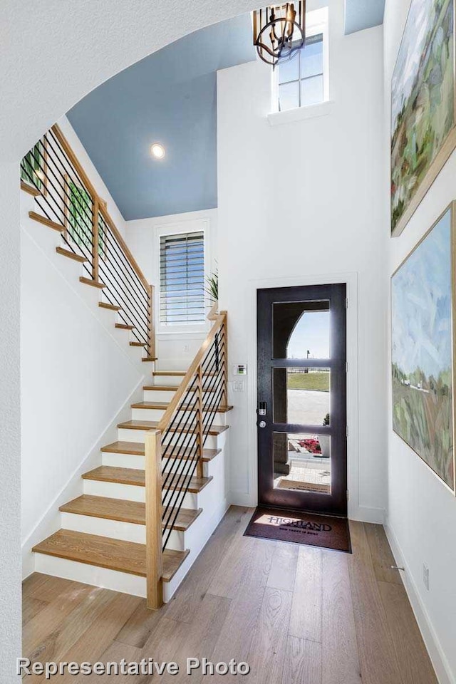 foyer entrance with wood-type flooring, an inviting chandelier, and a healthy amount of sunlight