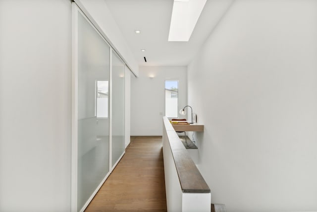 hallway featuring hardwood / wood-style floors and a skylight