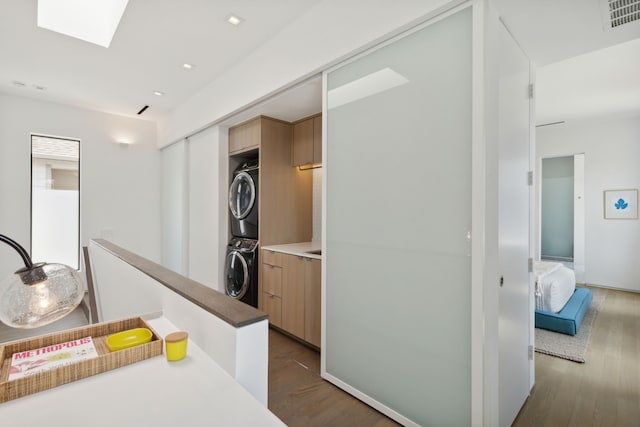 corridor with stacked washer and dryer, dark hardwood / wood-style flooring, and a skylight