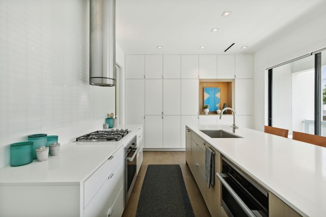 kitchen featuring sink, stainless steel appliances, white cabinetry, and hardwood / wood-style flooring