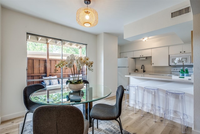 dining space featuring light wood-type flooring and sink