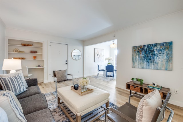 living room featuring built in shelves and light hardwood / wood-style flooring