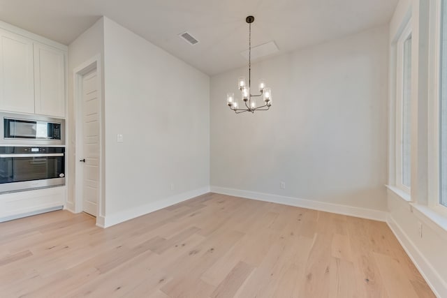 unfurnished dining area featuring an inviting chandelier and light wood-type flooring