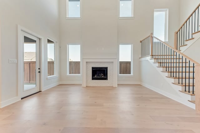 unfurnished living room featuring a high ceiling and light hardwood / wood-style floors