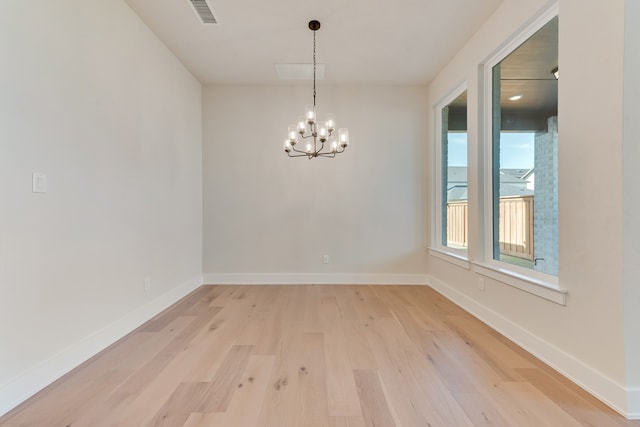 empty room with a notable chandelier, light hardwood / wood-style flooring, and a water view